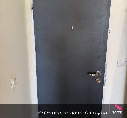 דלת מתכת עם ידית כסופה וקיר לבן